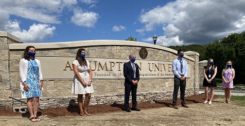 亚洲博彩网站 President Francesco Cesareo poses in front of the new University sign with students