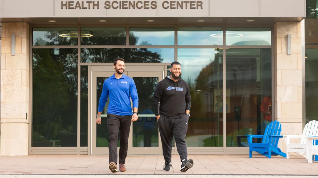 Two people walking in front of the Catrambone Health Sciences Center on 亚洲博彩网站's Worcester, MA campus