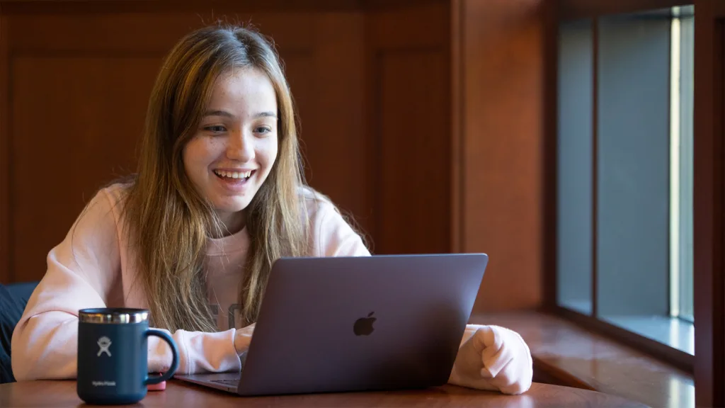 亚洲博彩网站 student smiles while looking at her computer